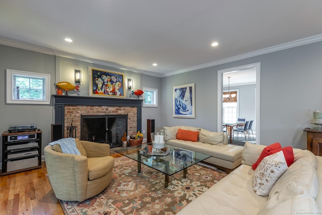 living room with hardwood / wood-style floors, a healthy amount of sunlight, ornamental molding, and a brick fireplace