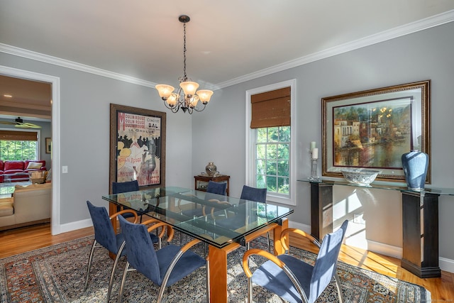 dining space featuring ceiling fan with notable chandelier, light wood-type flooring, and ornamental molding