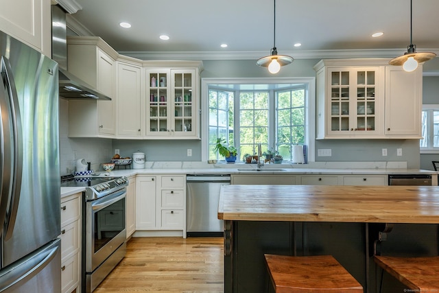 kitchen featuring sink, wall chimney exhaust hood, pendant lighting, and appliances with stainless steel finishes