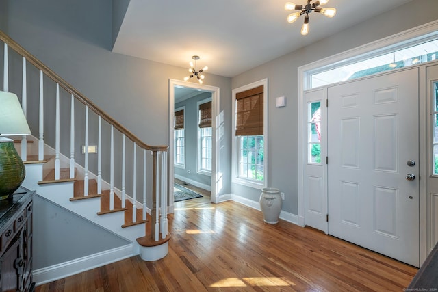 foyer entrance with hardwood / wood-style floors and a notable chandelier