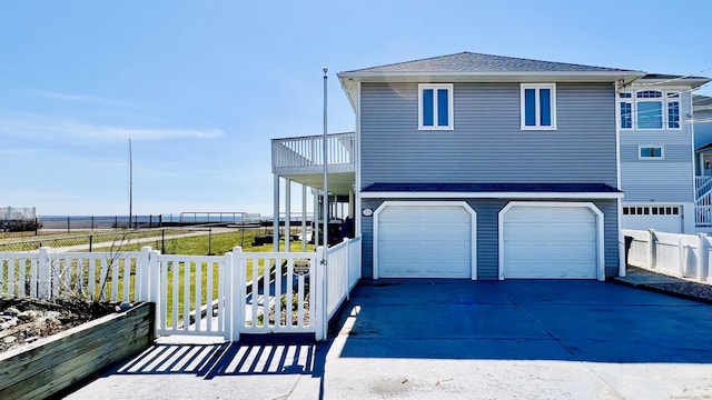 view of front of house featuring fence, concrete driveway, a shingled roof, a garage, and a balcony