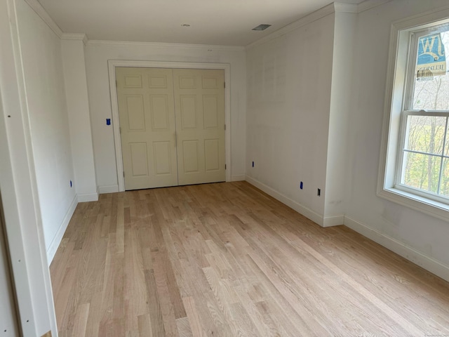 unfurnished bedroom featuring crown molding, a closet, and light hardwood / wood-style floors