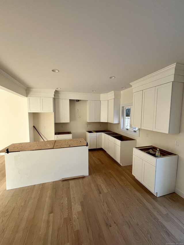 kitchen featuring light hardwood / wood-style floors, a kitchen island, white cabinetry, and ornamental molding