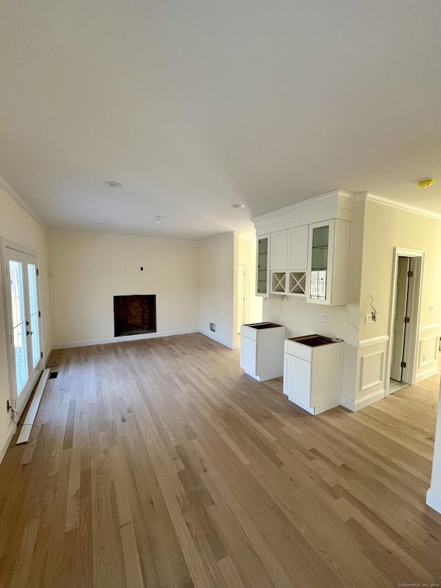 unfurnished living room with light hardwood / wood-style floors and crown molding