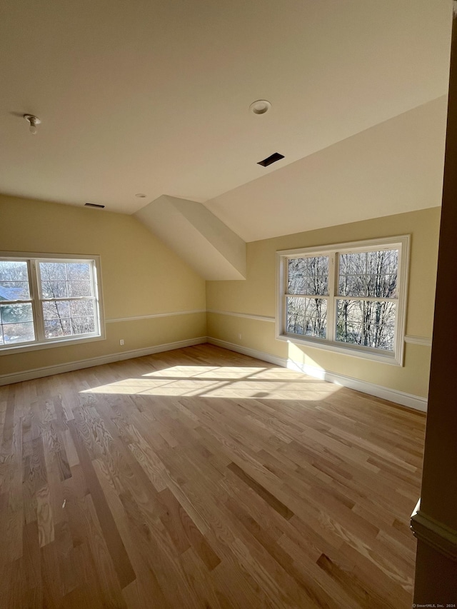 additional living space with light hardwood / wood-style flooring and lofted ceiling