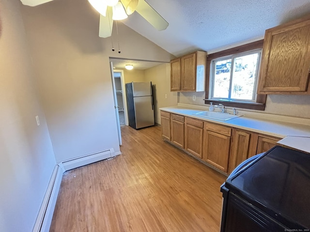 kitchen featuring sink, stainless steel fridge, black range with electric stovetop, a baseboard heating unit, and light hardwood / wood-style floors