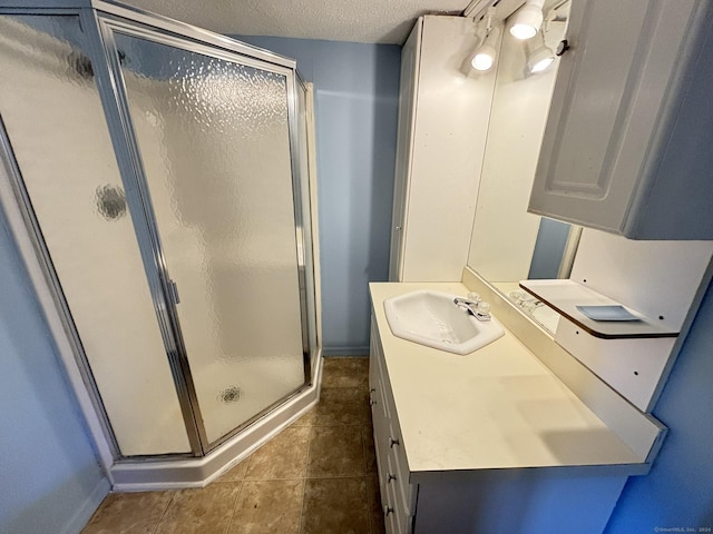 bathroom with vanity, a shower with shower door, tile patterned flooring, and a textured ceiling