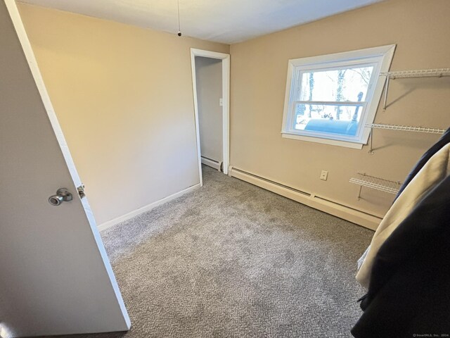 unfurnished bedroom featuring light colored carpet and a baseboard heating unit