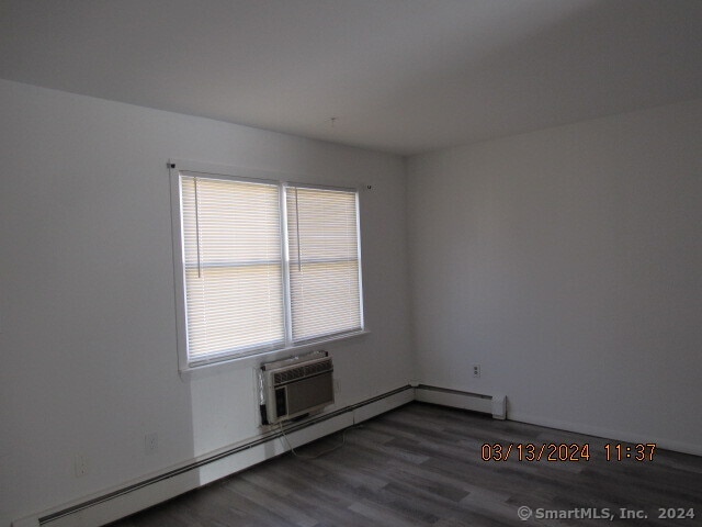 unfurnished room with baseboard heating and dark hardwood / wood-style floors