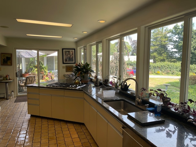 kitchen with stainless steel gas stovetop, sink, kitchen peninsula, and a healthy amount of sunlight