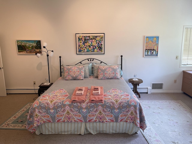 bedroom with a baseboard heating unit, carpet flooring, and visible vents