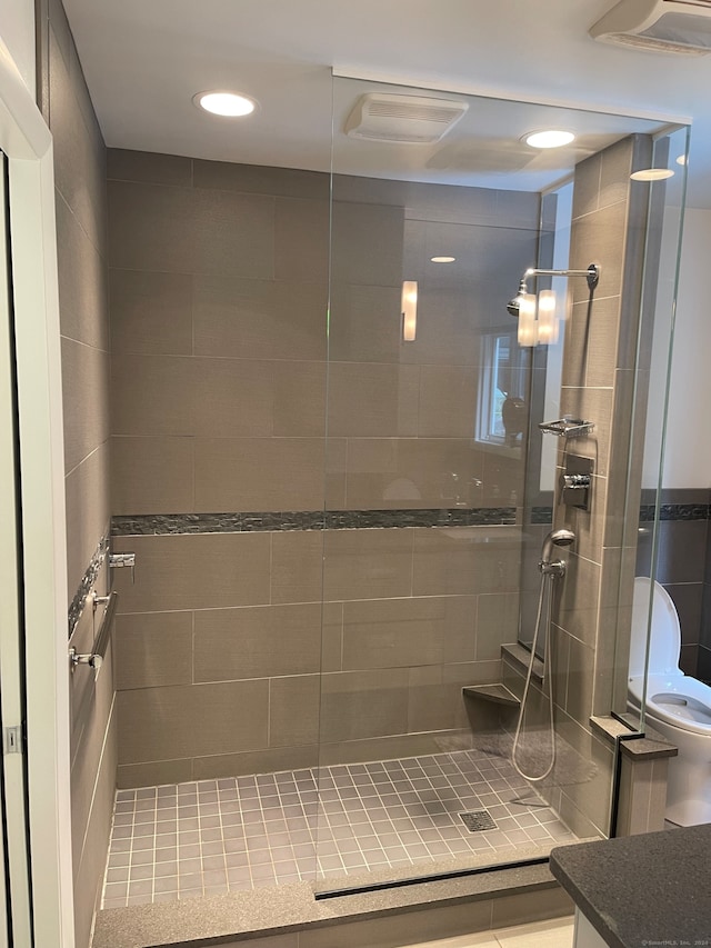 bathroom with tile patterned floors, vanity, tiled shower, and toilet