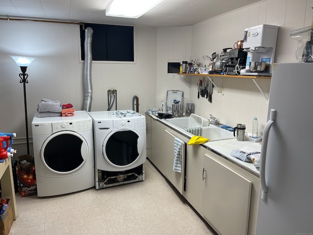 clothes washing area with sink, wooden walls, and independent washer and dryer