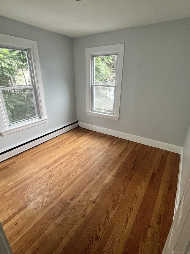 empty room featuring a baseboard radiator and light hardwood / wood-style flooring