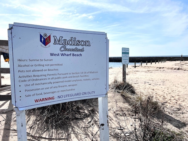 community sign with a beach view and a water view