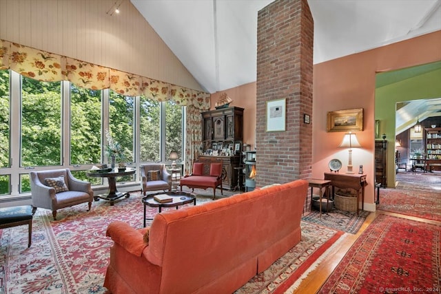 living room with brick wall, light hardwood / wood-style floors, and high vaulted ceiling