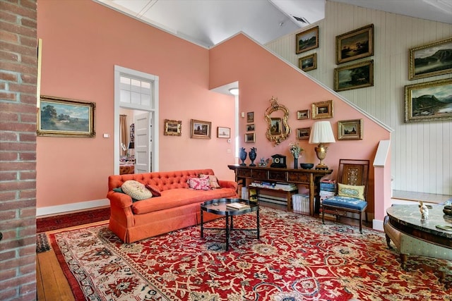 living room with brick wall, high vaulted ceiling, and dark hardwood / wood-style floors