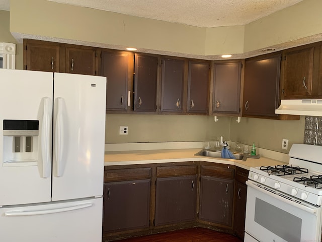 kitchen featuring white appliances, dark brown cabinetry, sink, and a textured ceiling