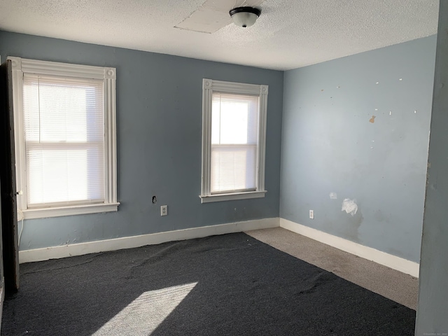 carpeted empty room featuring a textured ceiling