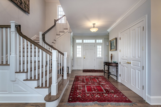 entrance foyer with ornamental molding, dark wood-type flooring, and a healthy amount of sunlight