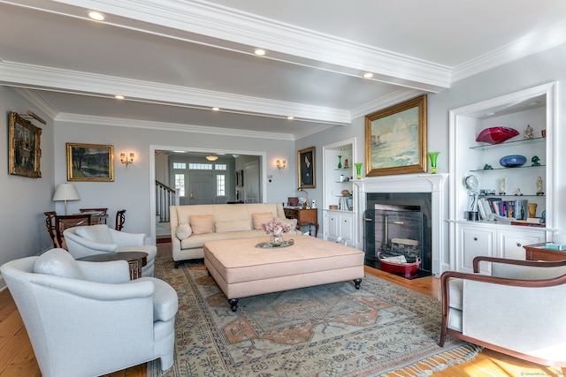 living room with wood-type flooring, ornamental molding, and built in shelves