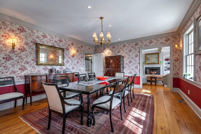 dining room with wood-type flooring, a chandelier, and crown molding