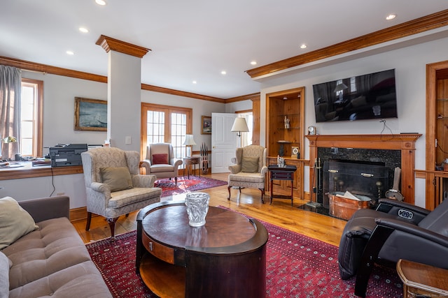 living room featuring crown molding, decorative columns, hardwood / wood-style floors, and a high end fireplace