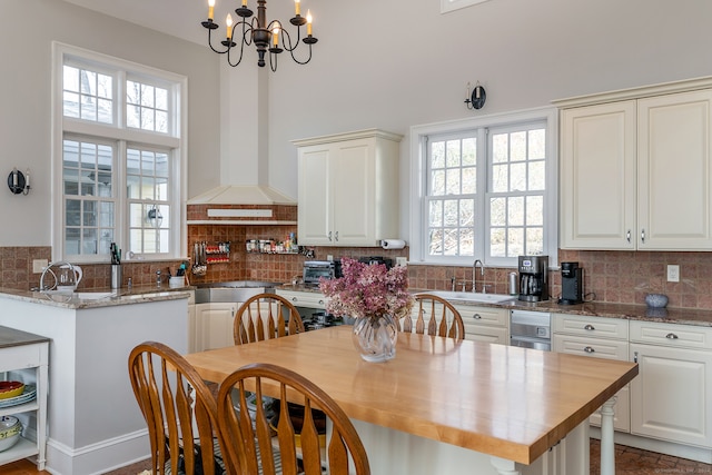 kitchen featuring a notable chandelier, a wealth of natural light, backsplash, and light stone counters