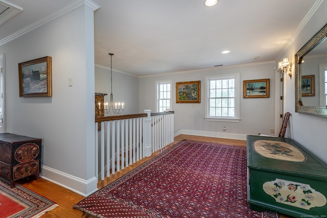 hallway featuring wood-type flooring, crown molding, and an inviting chandelier