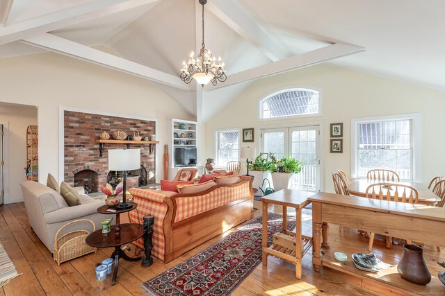 living room with beamed ceiling, light wood-type flooring, high vaulted ceiling, a notable chandelier, and a fireplace