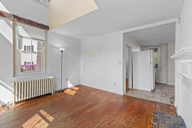 empty room featuring radiator, hardwood / wood-style floors, and a fireplace