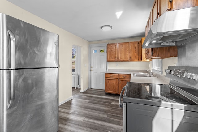 kitchen featuring radiator heating unit, electric range oven, dark wood-type flooring, stainless steel refrigerator, and sink