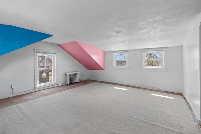 bonus room featuring light carpet, vaulted ceiling, radiator heating unit, and a wealth of natural light