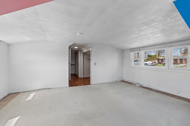 carpeted empty room with vaulted ceiling