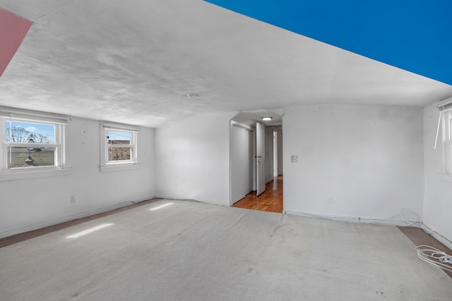 carpeted spare room featuring vaulted ceiling