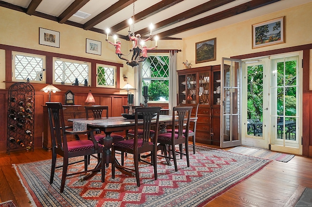 dining space with beam ceiling, light hardwood / wood-style flooring, an inviting chandelier, and plenty of natural light