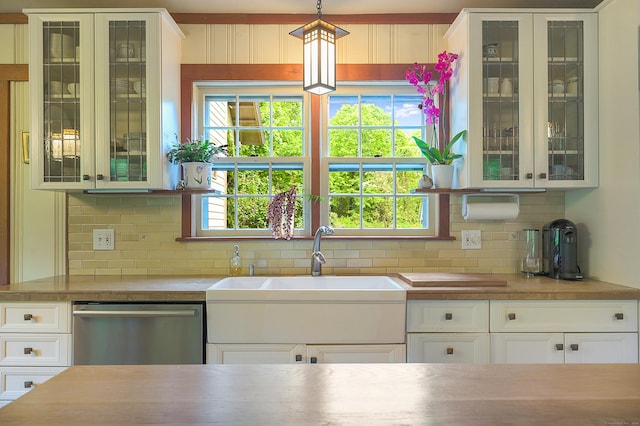 kitchen with pendant lighting, white cabinetry, stainless steel dishwasher, and tasteful backsplash