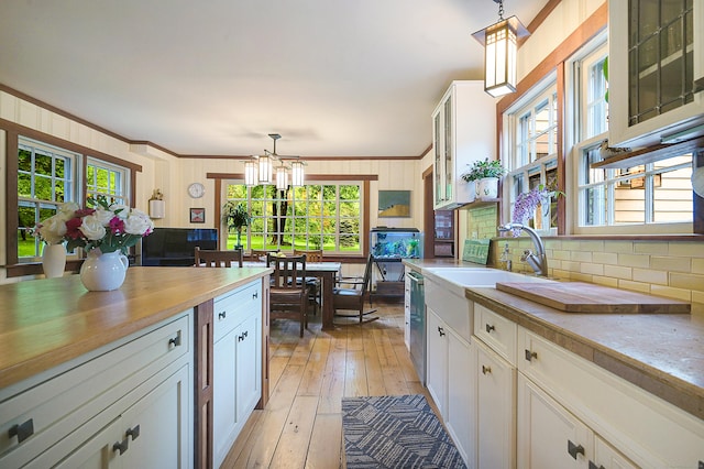 kitchen with a chandelier, a healthy amount of sunlight, white cabinets, and hanging light fixtures