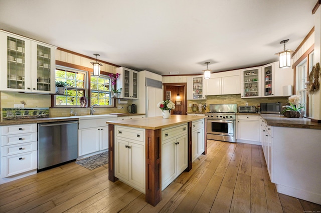 kitchen featuring sink, stainless steel appliances, light hardwood / wood-style flooring, pendant lighting, and white cabinets