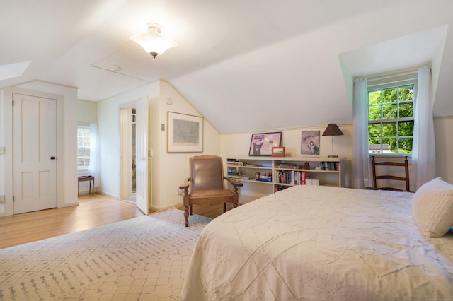 bedroom with light wood-type flooring and vaulted ceiling