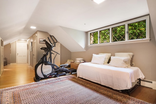 bedroom featuring a baseboard radiator, lofted ceiling, and light wood-type flooring