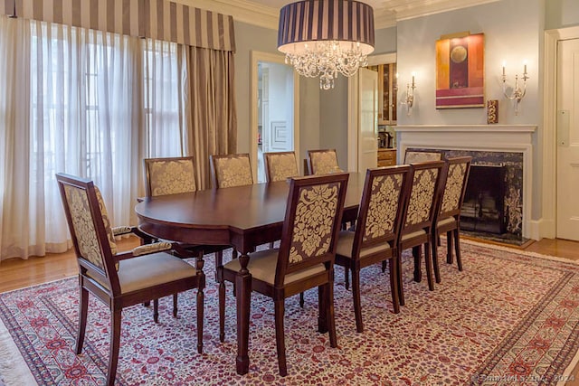 dining space with a wealth of natural light, crown molding, light hardwood / wood-style flooring, and an inviting chandelier