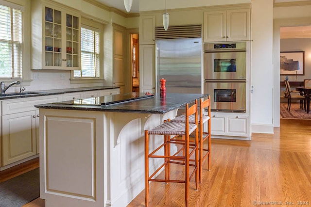 kitchen featuring a center island, dark stone counters, light hardwood / wood-style flooring, a breakfast bar area, and appliances with stainless steel finishes