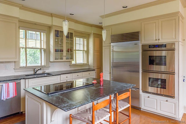 kitchen featuring decorative light fixtures, backsplash, light wood-type flooring, stainless steel appliances, and a center island