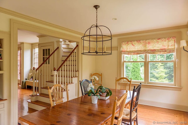 dining area with an inviting chandelier, ornamental molding, and light wood-type flooring