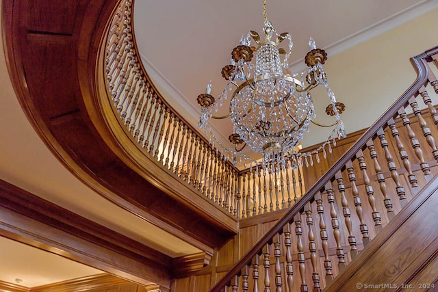 stairs featuring a chandelier, a high ceiling, and crown molding