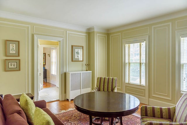 living room featuring radiator heating unit, light hardwood / wood-style floors, and a wealth of natural light