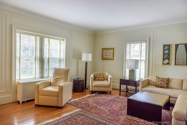 living room featuring ornamental molding, a wealth of natural light, and light hardwood / wood-style flooring