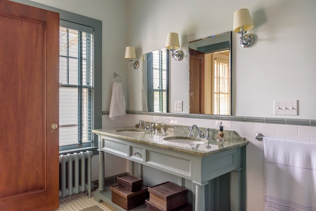 bathroom with tile walls, tile floors, dual vanity, and radiator heating unit