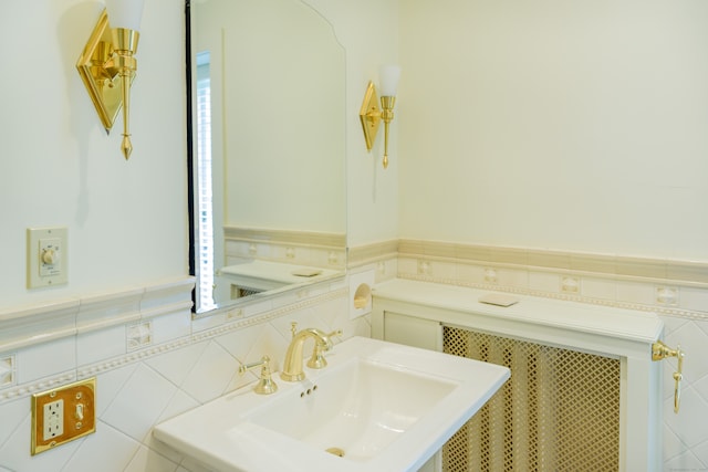 bathroom featuring radiator, sink, and tile walls